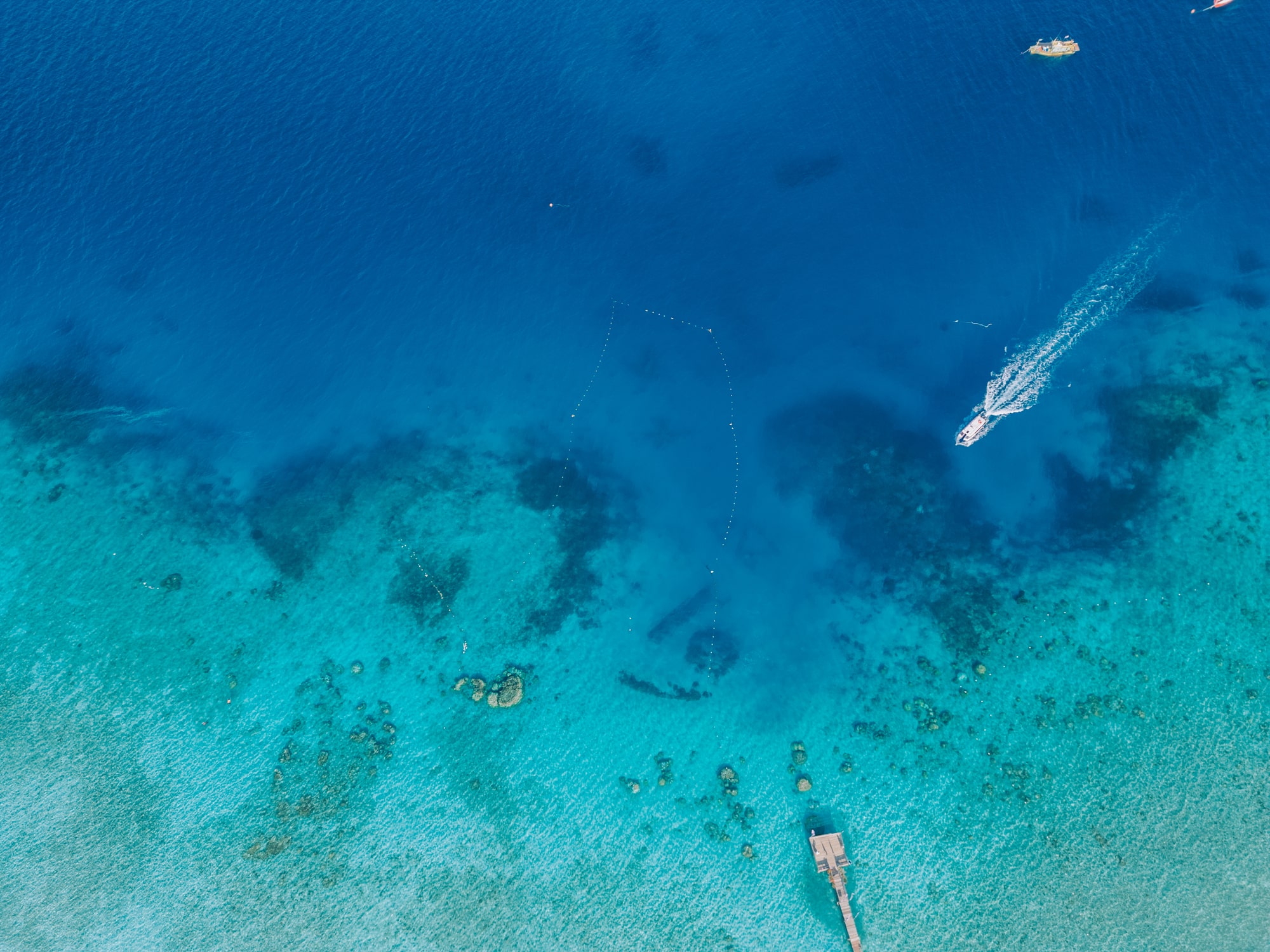 Drone point of view anchored boats at lagoon with pier in lang tengah island, malaysia